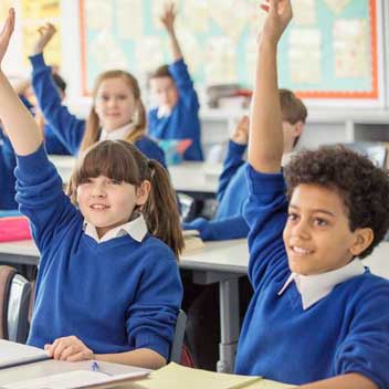School children rasing hand in class